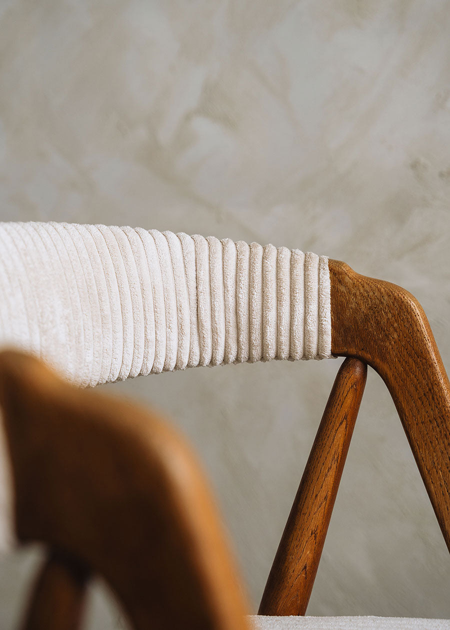 Silla de madera de haya tapizada en pana beige.