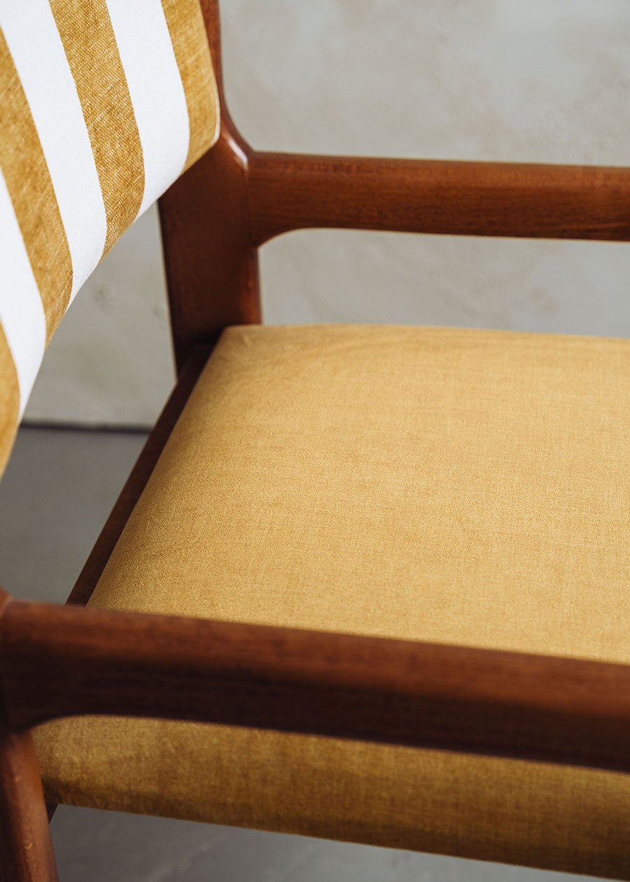 Silla de madera de haya con asiento tapizado en tela mostaza y respaldo con estampado de rayas.