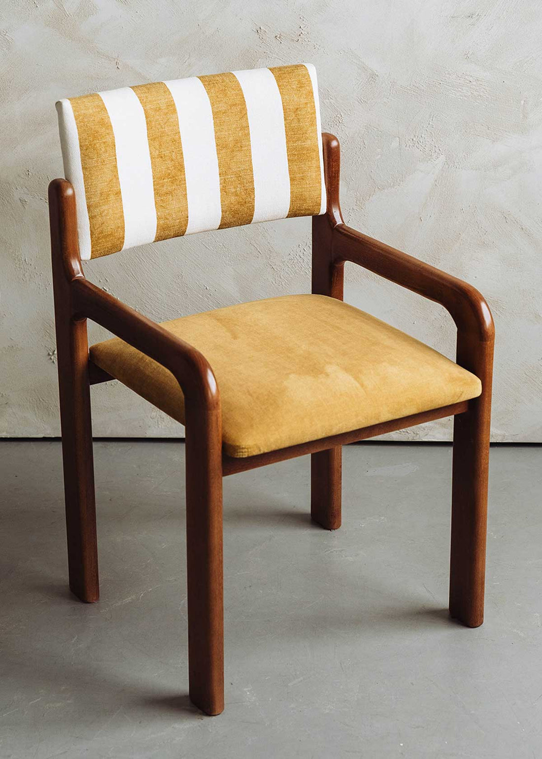 Silla de madera de haya con asiento tapizado en tela mostaza y respaldo con estampado de rayas.