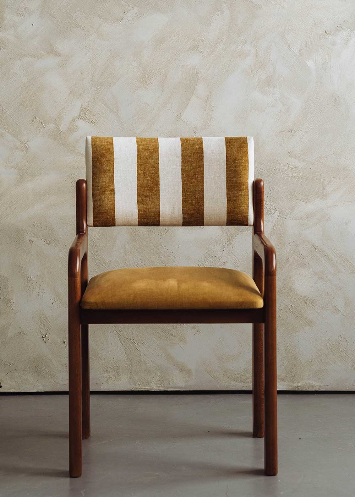 Silla de madera de haya con asiento tapizado en tela mostaza y respaldo con estampado de rayas.