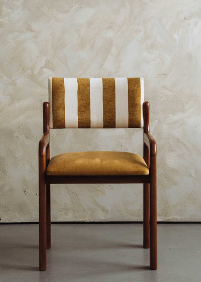 Silla de madera de haya con asiento tapizado en tela mostaza y respaldo con estampado de rayas.