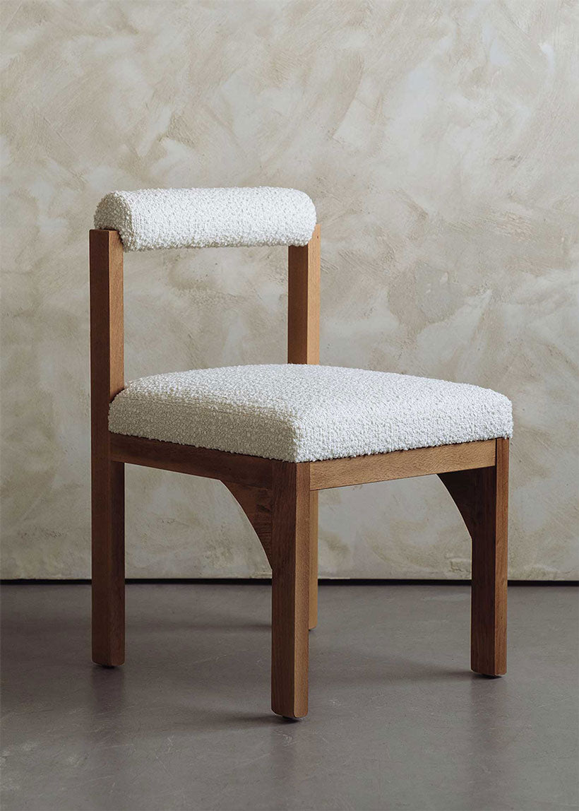 Silla de madera de haya tapizada en bouclé blanco con respaldo cilíndrico.