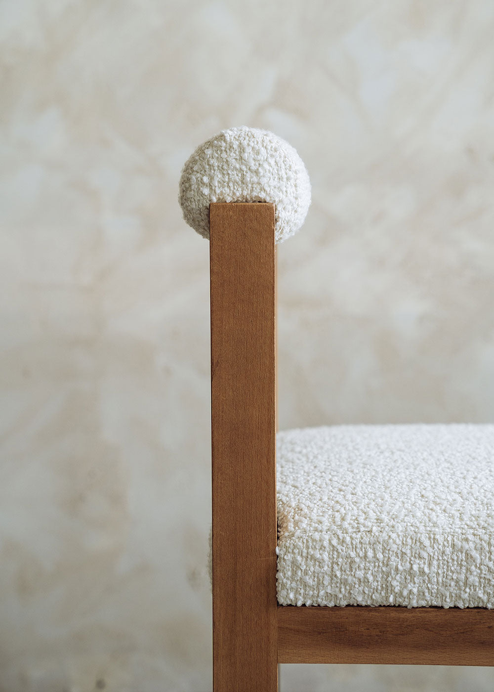 Silla de madera de haya tapizada en bouclé blanco con respaldo cilíndrico.