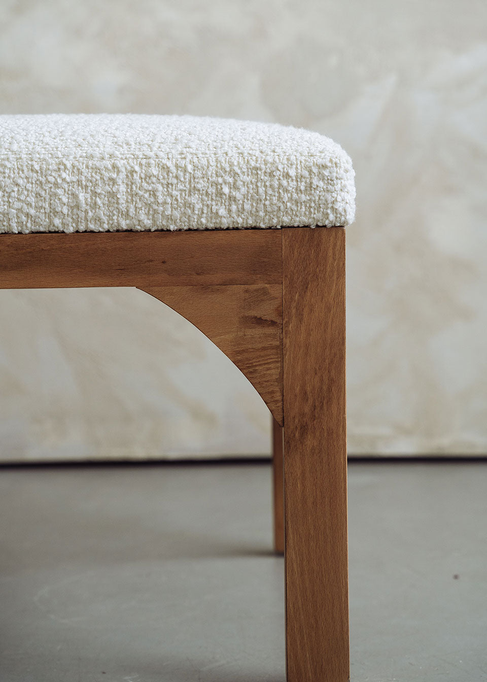 Silla de madera de haya tapizada en bouclé blanco con respaldo cilíndrico.