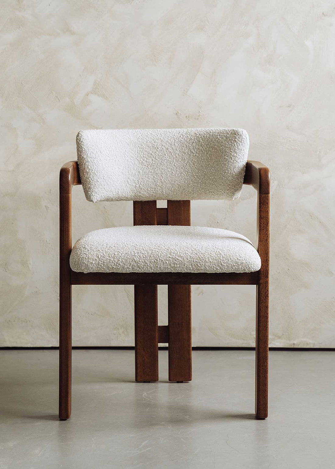Silla de madera de haya con reposabrazos tapizada en terciopelo beige.