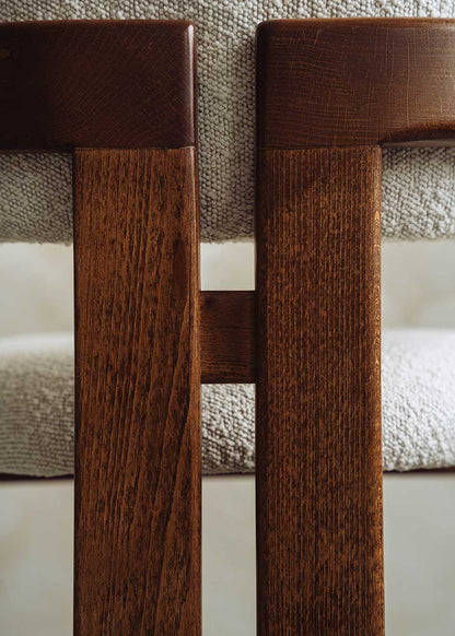 Silla de madera de haya con reposabrazos tapizada en terciopelo beige.