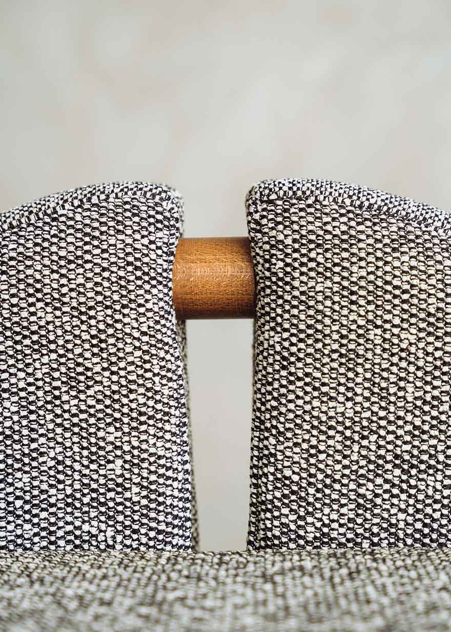 Taburete tapizado en tela jaspeada blanca y negra con estructura de madera de haya. Un taburete alto con respaldo y reposapiés incorporado.