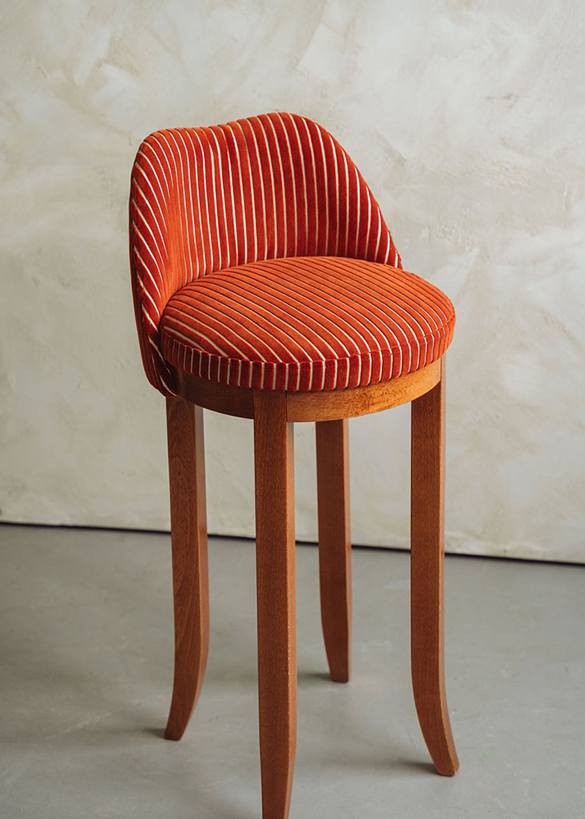 Taburete con respaldo tapizado en terciopelo caldera rayado con estructura de madera de haya.