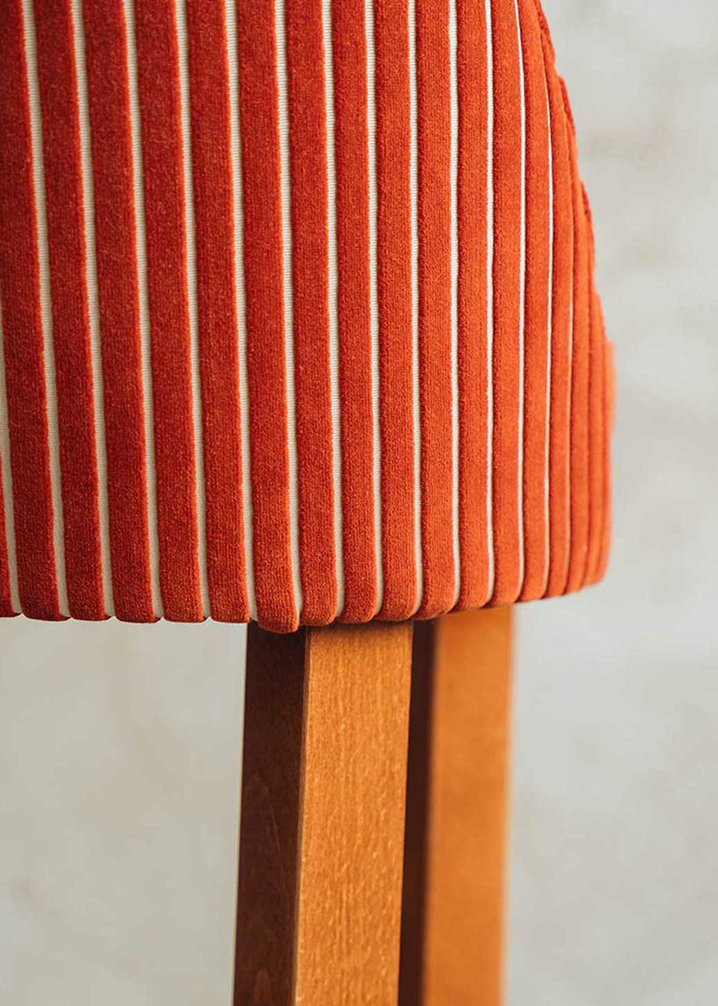 Taburete con respaldo tapizado en terciopelo caldera rayado con estructura de madera de haya.