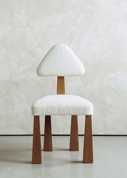 Silla de madera de haya tapizada en bouclé blanco con respaldo triangular.