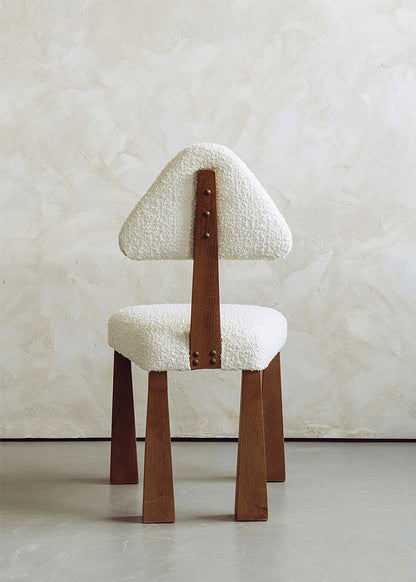 Silla de madera de haya tapizada en bouclé blanco con respaldo triangular.
