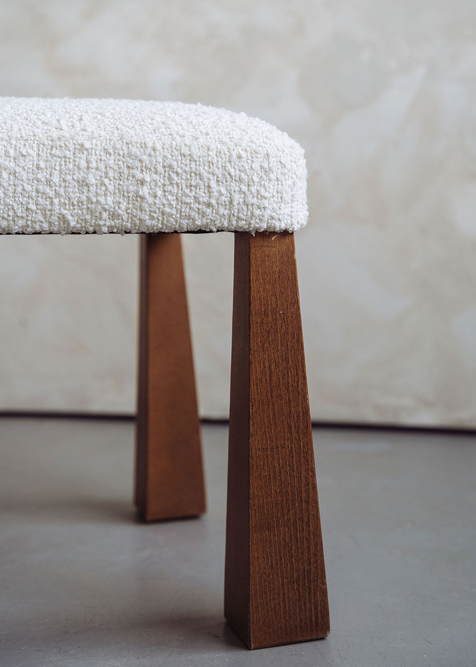 Silla de madera de haya tapizada en bouclé blanco con respaldo triangular.