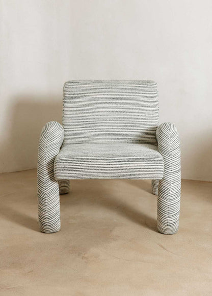 Butaca con reposabrazos tapizado con tela rayada azul y blanca.