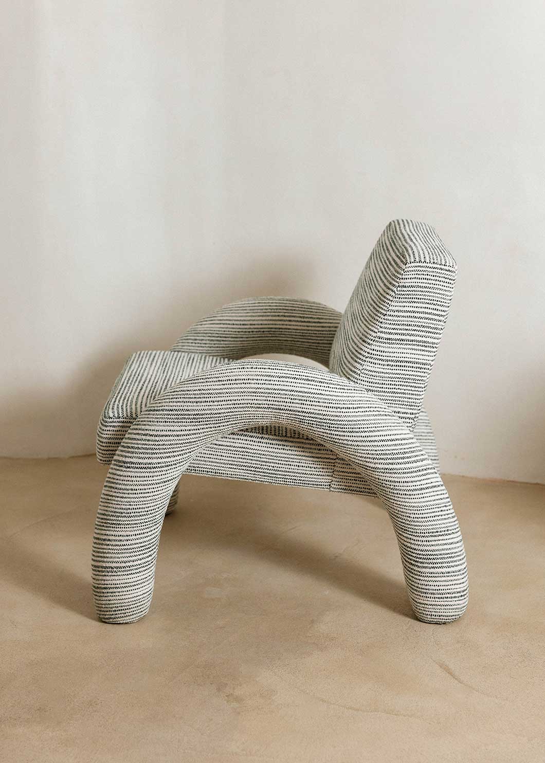 Butaca con reposabrazos tapizado con tela rayada azul y blanca.