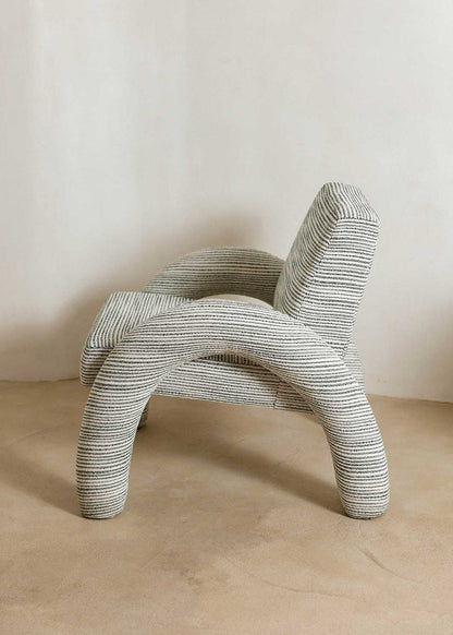 Butaca con reposabrazos tapizado con tela rayada azul y blanca.