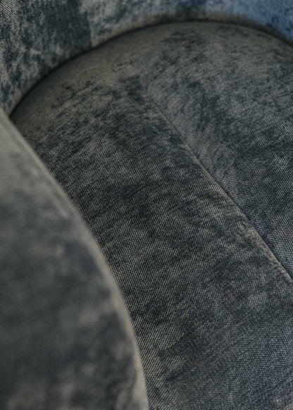 Sillón tapizado con tela de chenilla azul.