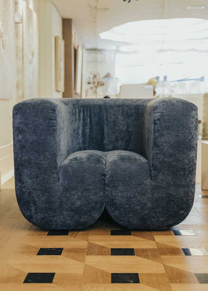 Sillón tapizado con tela de chenilla azul.