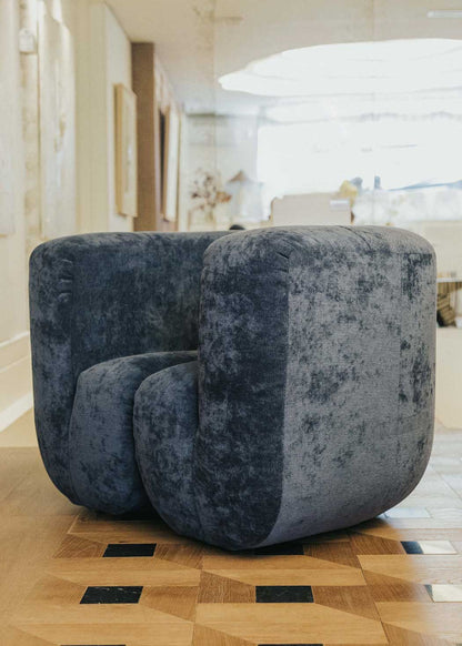 Sillón tapizado con tela de chenilla azul.