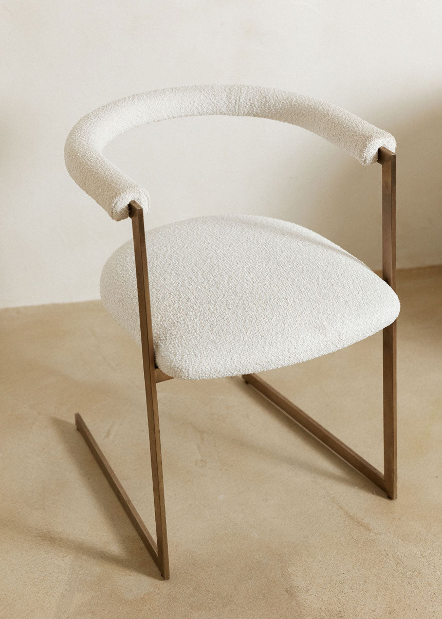 Silla de latón con acabado cepillado, tapizada con bouclé blanco.