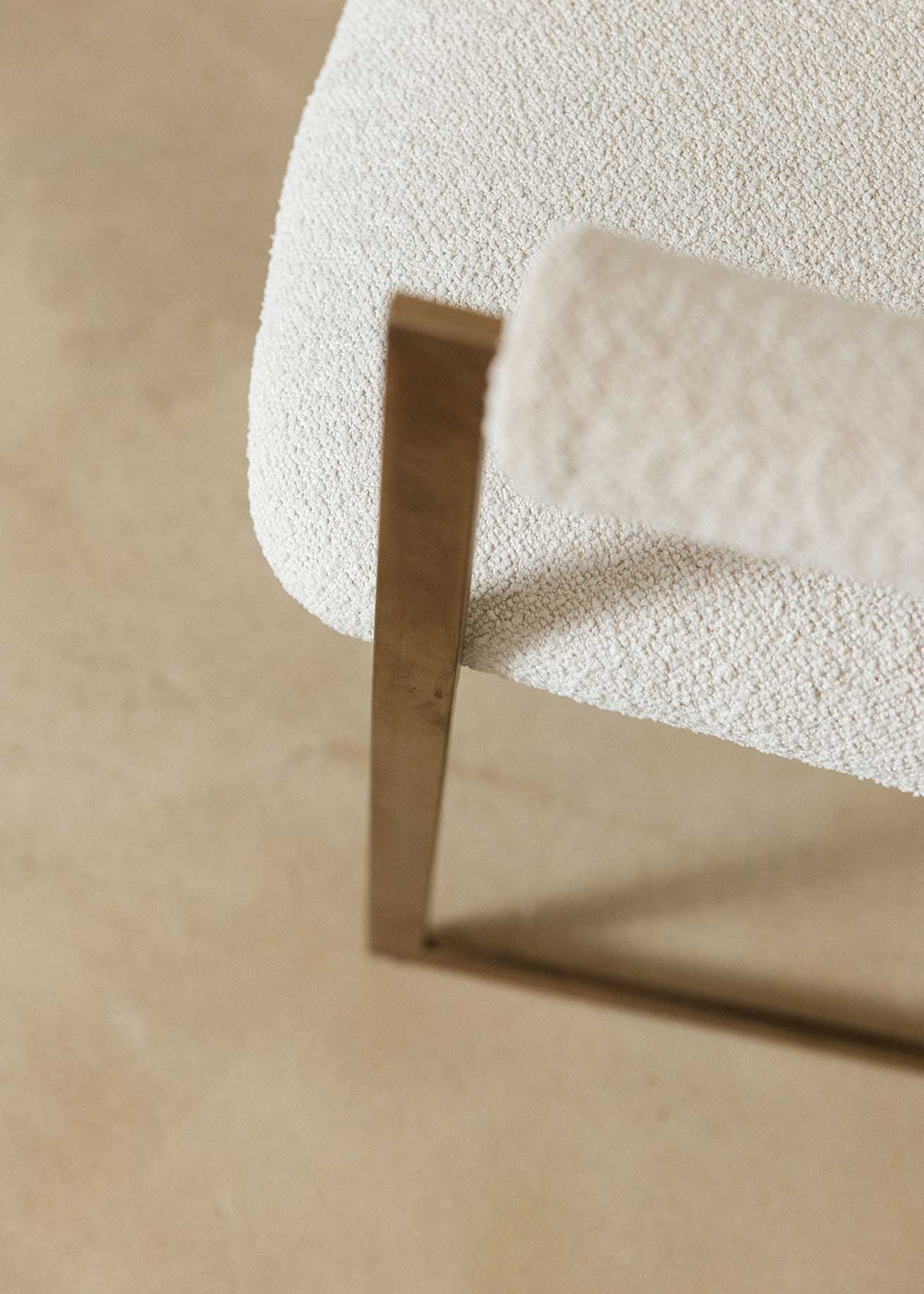 Silla de latón con acabado cepillado, tapizada con bouclé blanco.