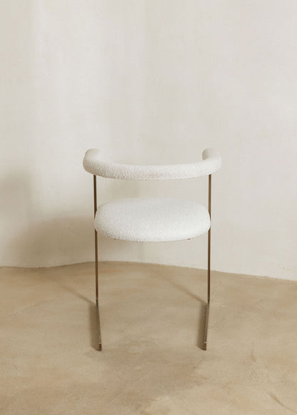 Silla de latón con acabado cepillado, tapizada con bouclé blanco.