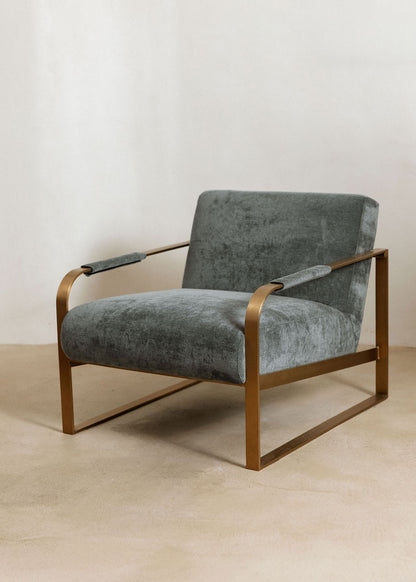 Butaca con reposabrazos tapizado con tela de chenilla azul.