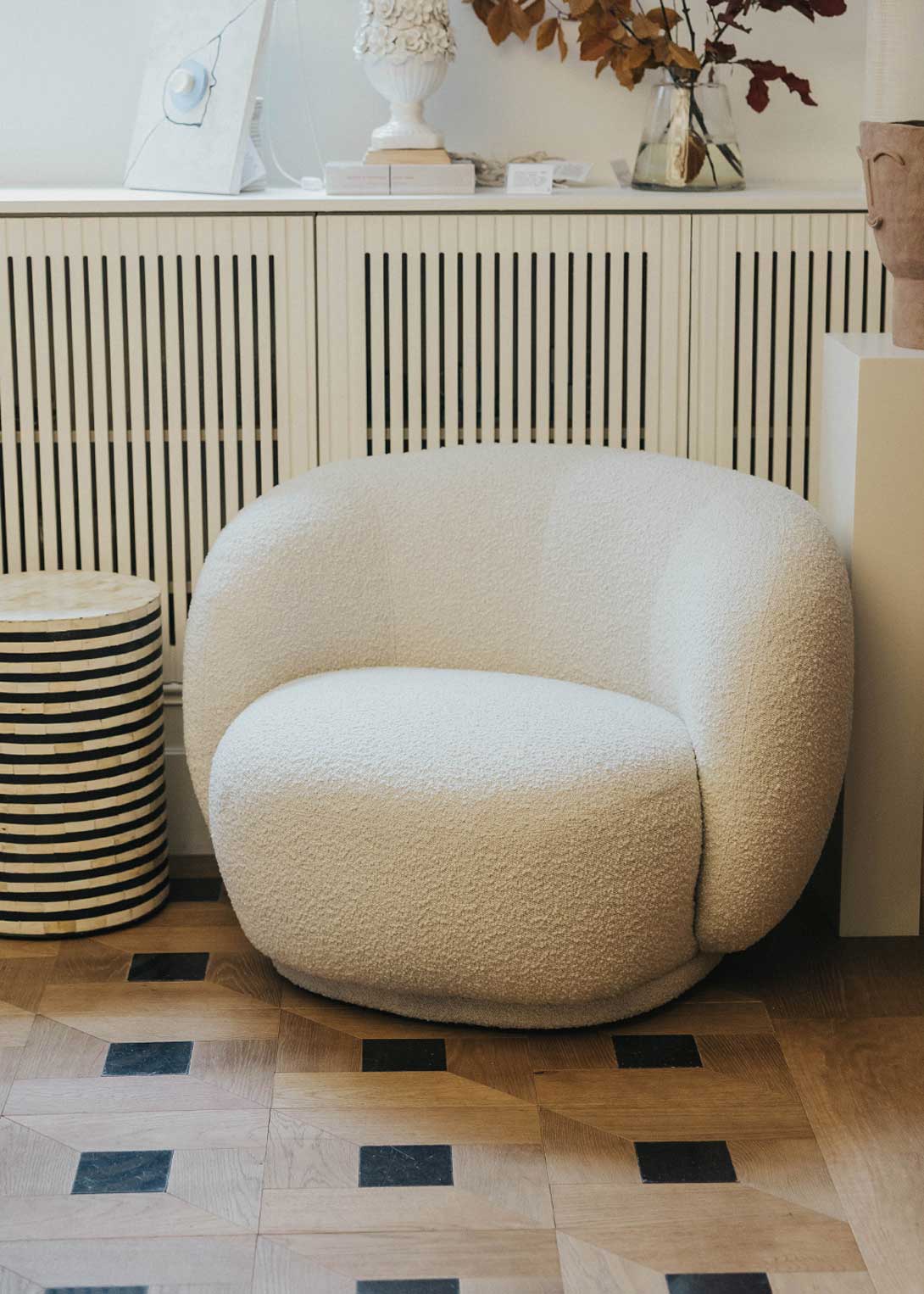Sillón tapizado con tela bouclé blanca.