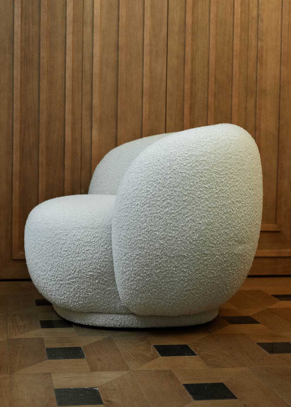 Sillón tapizado con tela bouclé blanca.