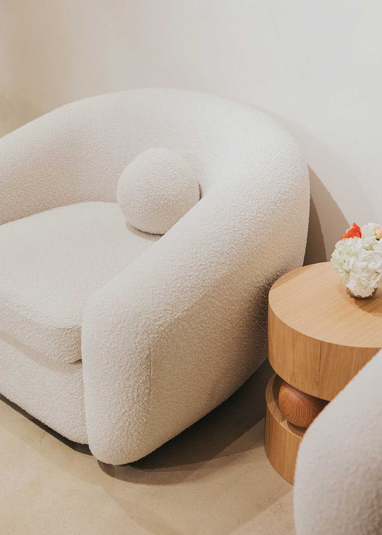 Sillón tapizado con tela bouclé blanca.