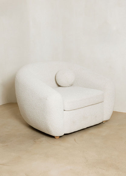 Sillón tapizado con tela bouclé blanca.