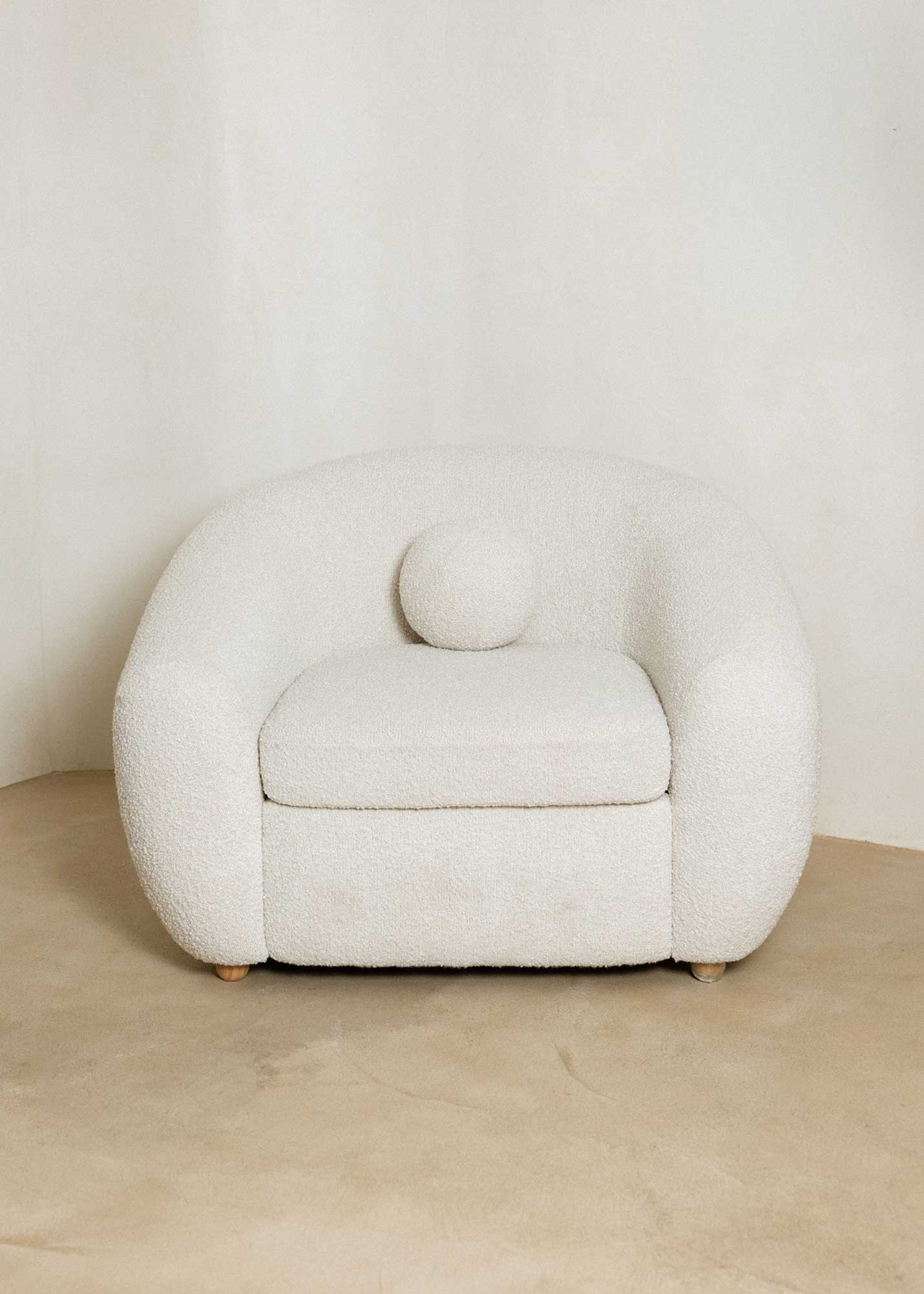 Sillón tapizado con tela bouclé blanca.