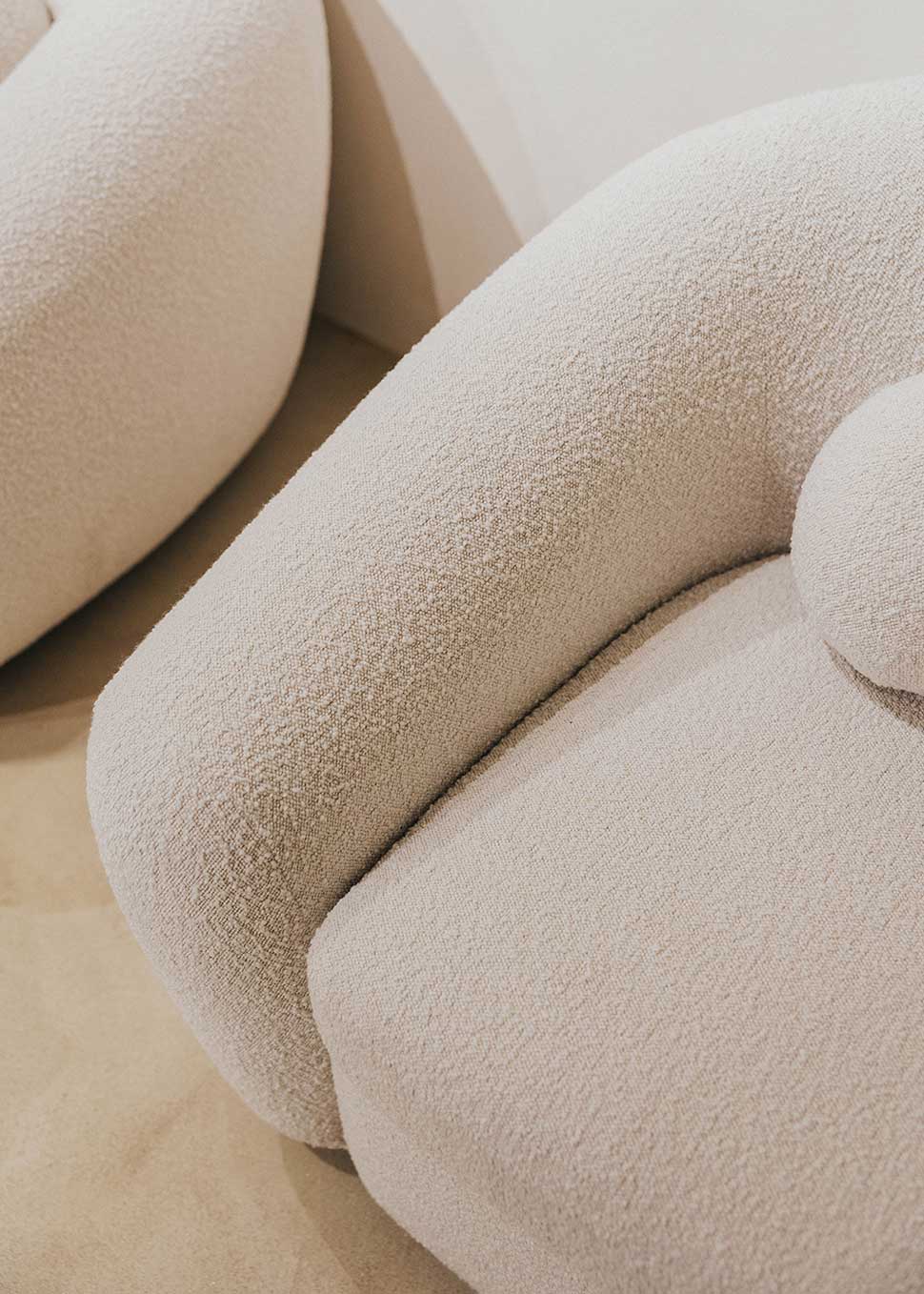 Sillón tapizado con tela bouclé blanca.