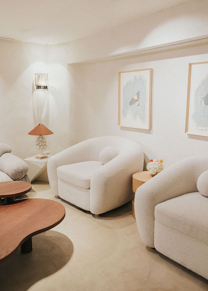 Sillón tapizado con tela bouclé blanca.