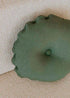 Almohadón circular con capitoné, tapizado en tela verde.