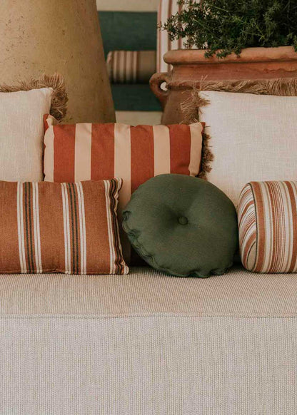 Almohadón circular con capitoné, tapizado en tela verde.