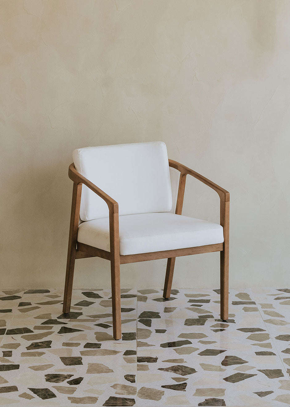 Butaca de exterior en madera de haya con reposabrazos tapizada en tela blanca.