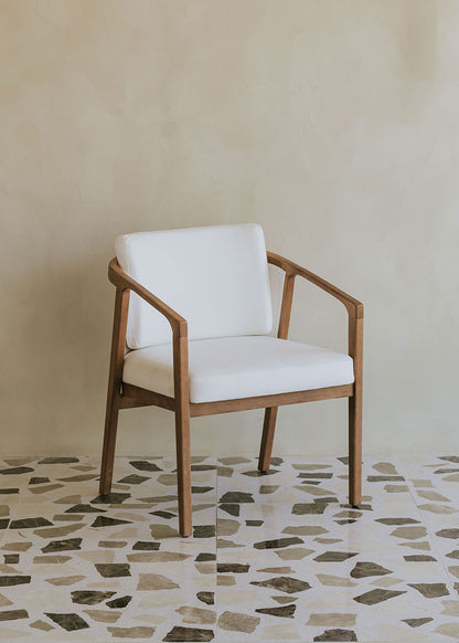 Butaca de exterior en madera de haya con reposabrazos tapizada en tela blanca.