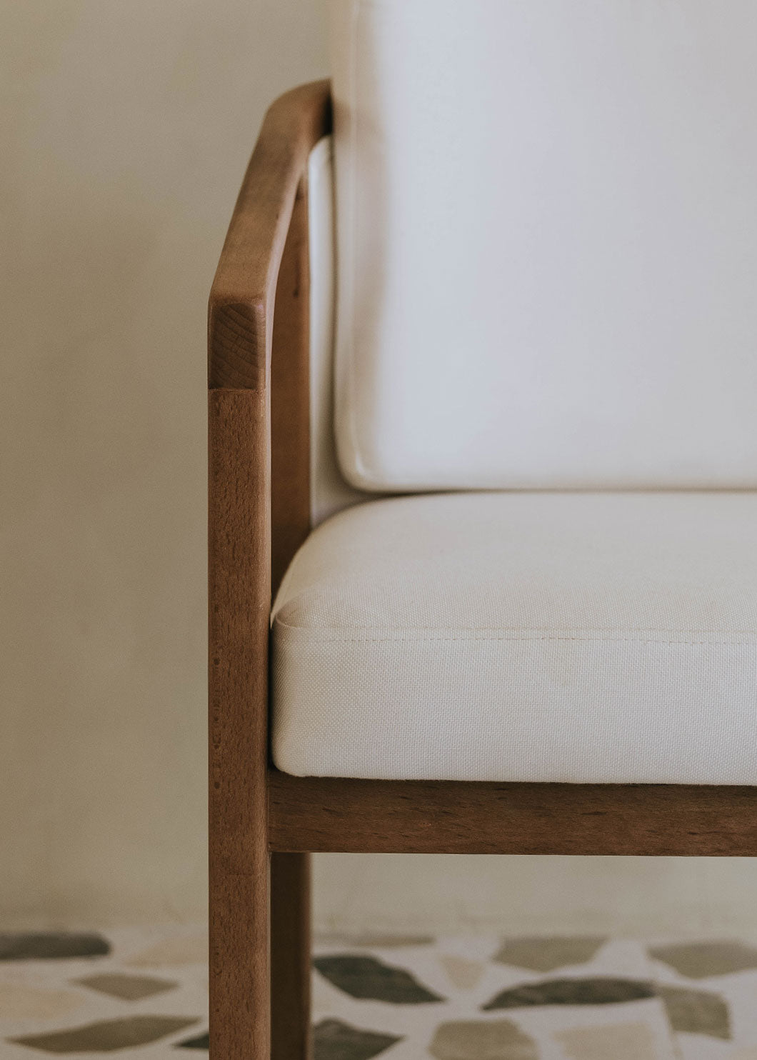 Butaca de exterior en madera de haya con reposabrazos tapizada en tela blanca.