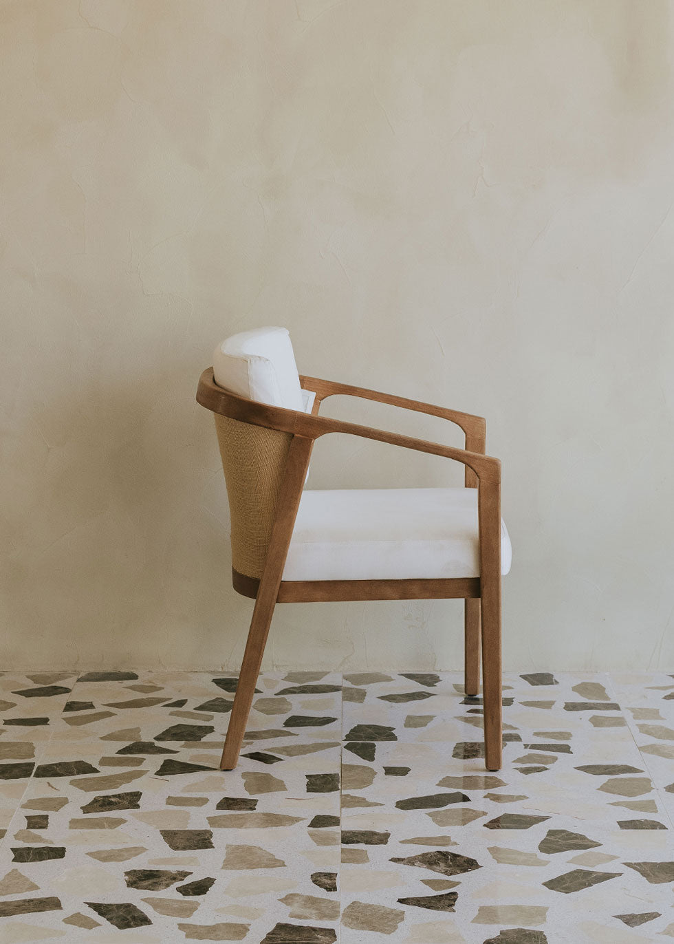 Butaca de exterior en madera de haya con reposabrazos tapizada en tela blanca.