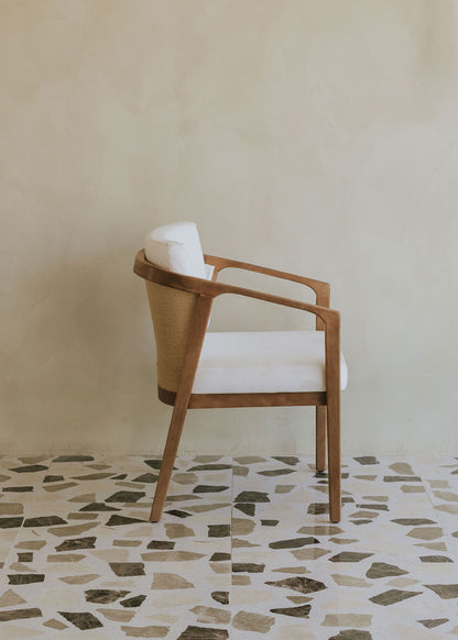 Butaca de exterior en madera de haya con reposabrazos tapizada en tela blanca.