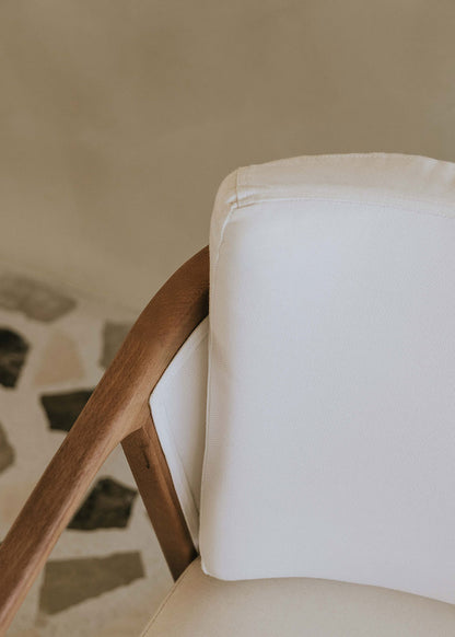 Butaca de exterior en madera de haya con reposabrazos tapizada en tela blanca.