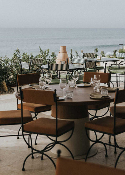 Mesa de comedor circular con sobre de madera de haya maciza barnizada y pie de madera con revestimiento cementoso en color blanco.