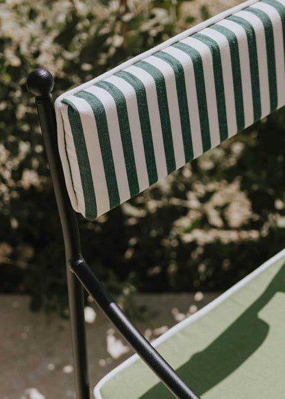 Silla de exterior con estructura de hierro negro tapizada en verde y blanco.