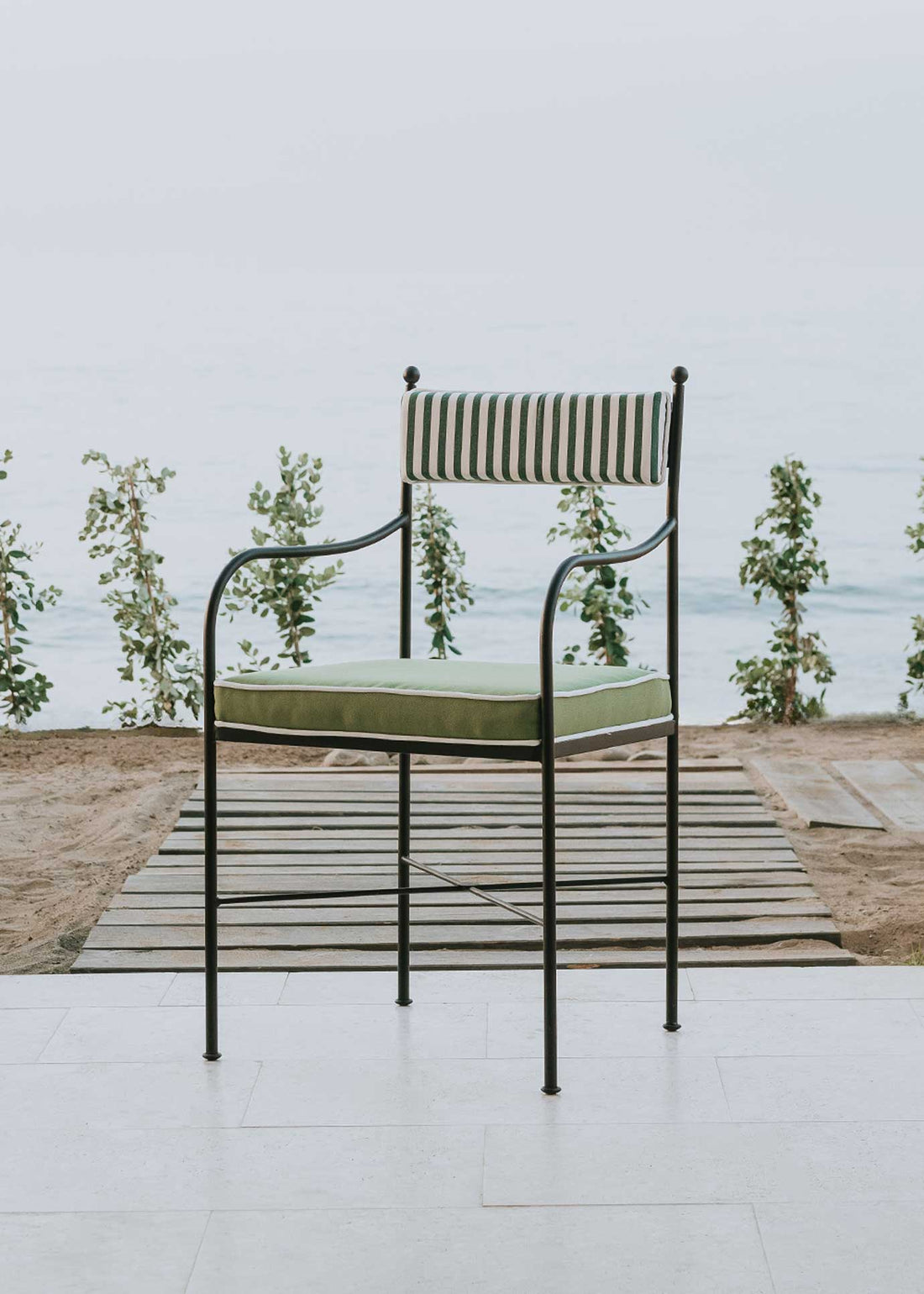 Silla de exterior con estructura de hierro negro tapizada en verde y blanco.