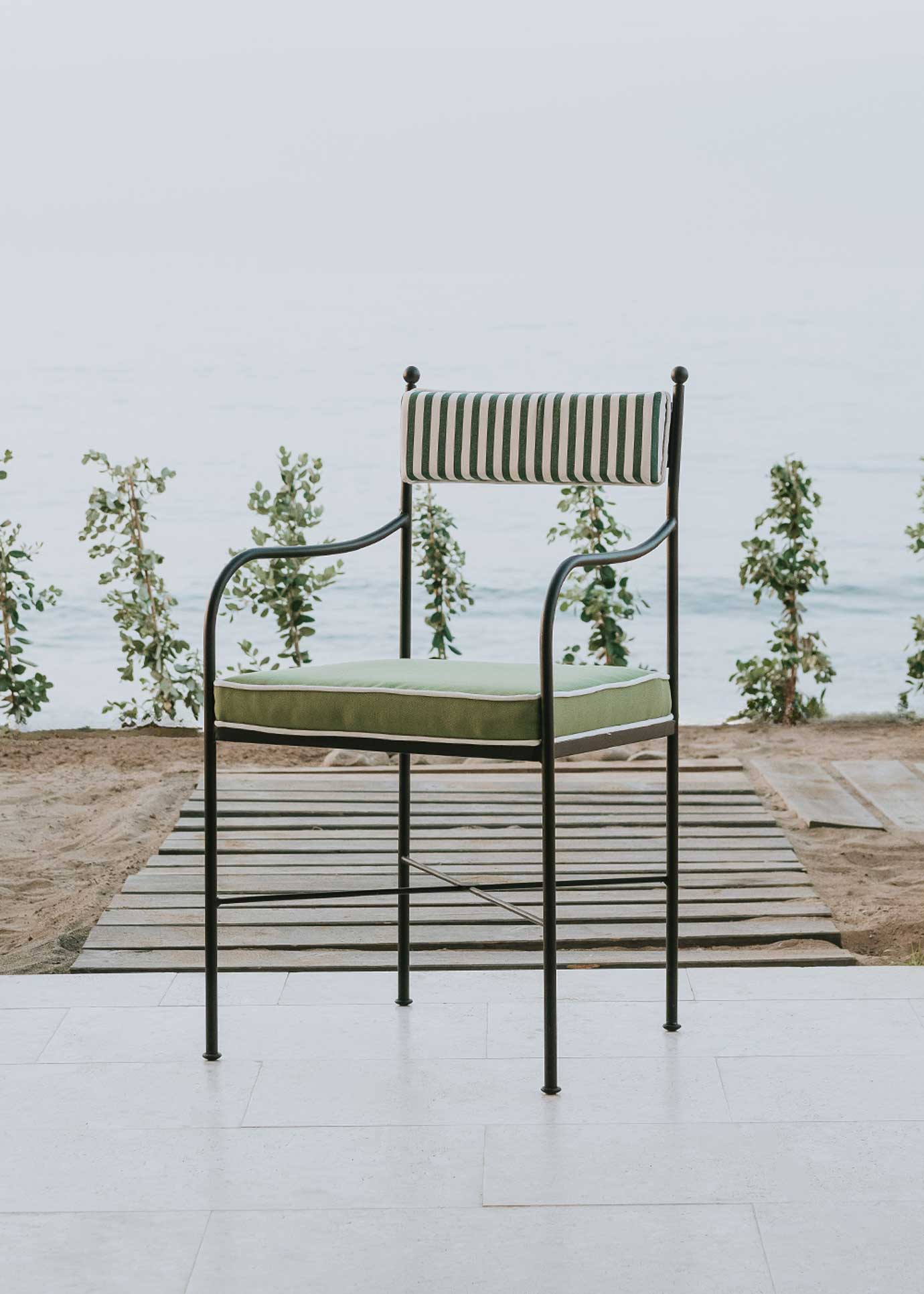 Silla de exterior con estructura de hierro negro tapizada en verde y blanco.