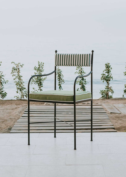 Silla de exterior con estructura de hierro negro tapizada en verde y blanco.