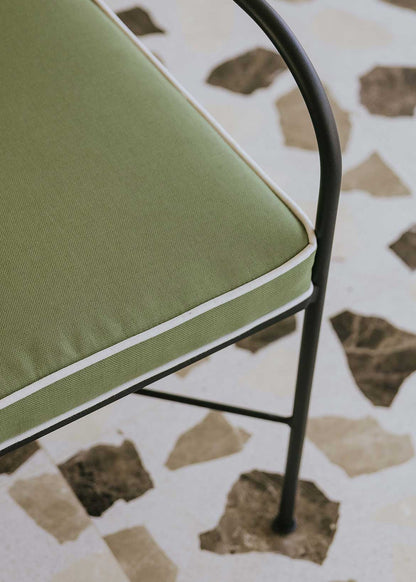 Silla de exterior con estructura de hierro negro tapizada en verde y blanco.
