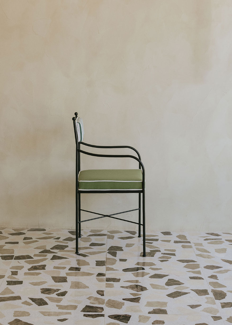 Silla de exterior con estructura de hierro negro tapizada en verde y blanco.