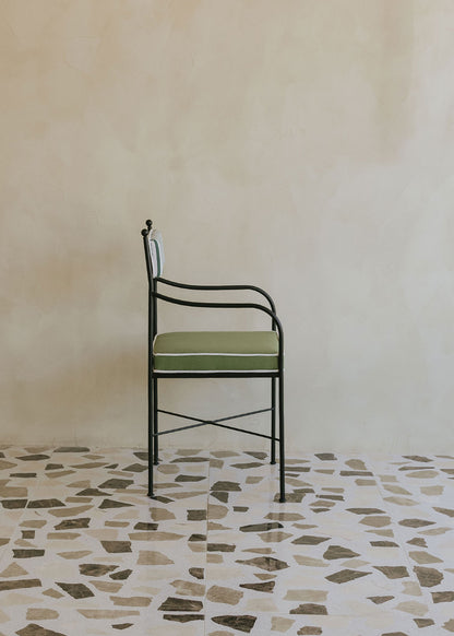 Silla de exterior con estructura de hierro negro tapizada en verde y blanco.