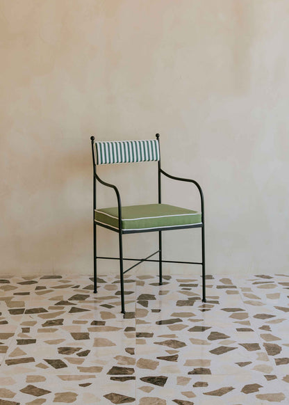 Silla de exterior con estructura de hierro negro tapizada en verde y blanco.
